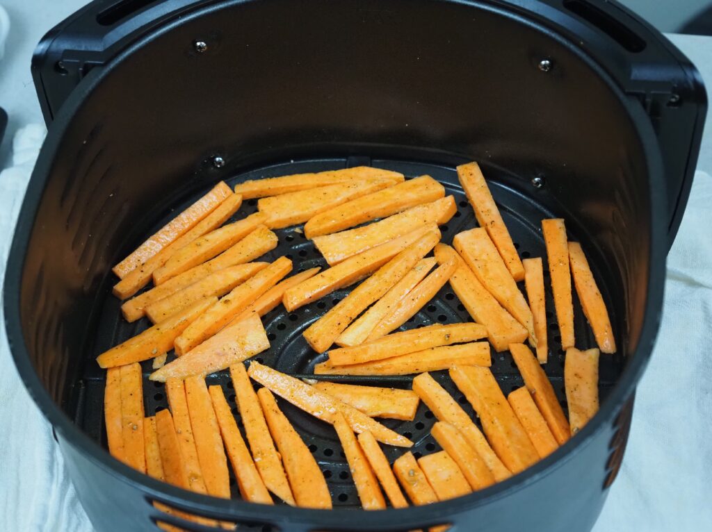 Seasoned sweet potato fries kept in air fryer basket and ready to get into air fryer.