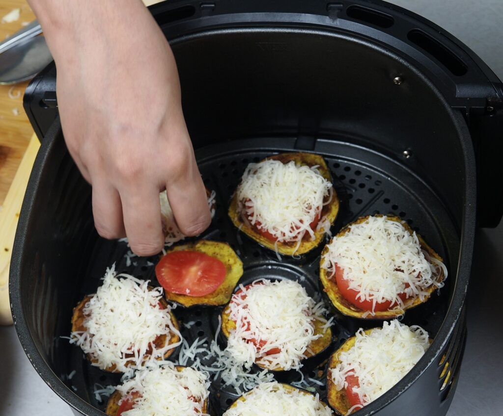 Topping eggplant slices with tomato slice and mozzarella cheese.